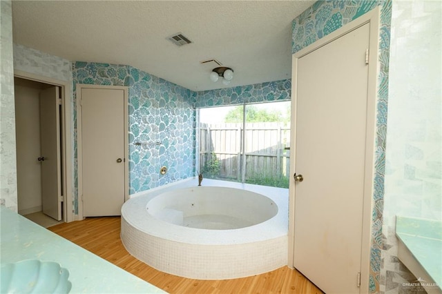 15220 Wilson Rd, Harlingen, TX 78552 - full bathroom with wallpapered walls, a whirlpool tub, wood finished floors, and a textured ceiling