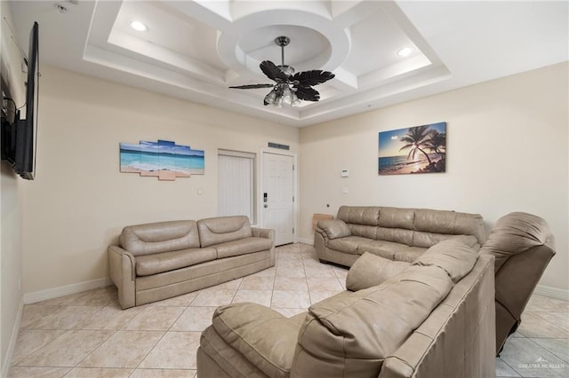 tiled living room featuring ceiling fan and a raised ceiling