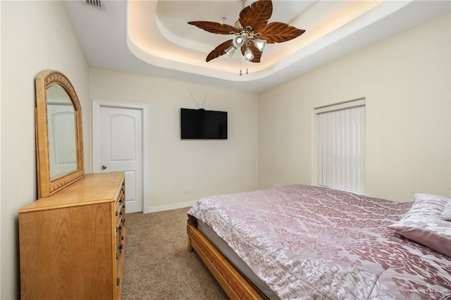 carpeted bedroom with a tray ceiling and ceiling fan