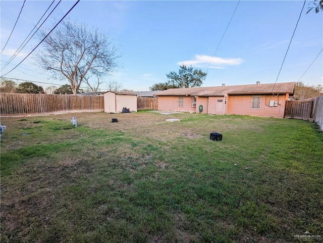 view of yard featuring an outbuilding, a fenced backyard, and a shed