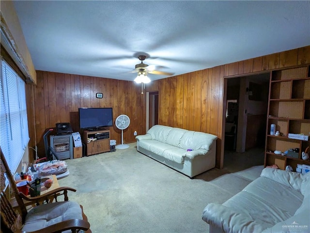 living area featuring ceiling fan, light colored carpet, and wood walls