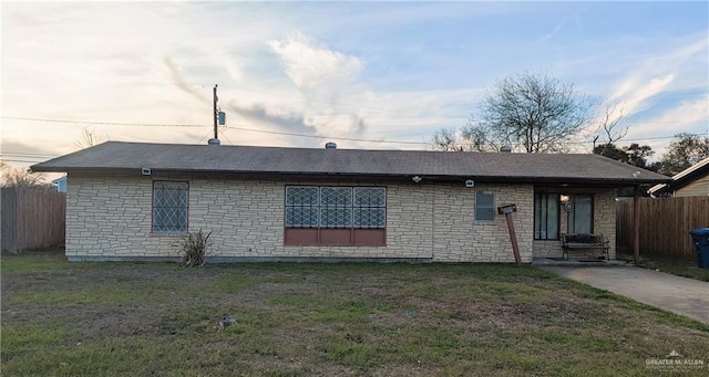 rear view of property featuring a yard and fence