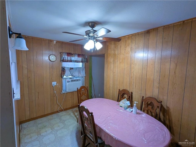 dining space with wooden walls, cooling unit, baseboards, ceiling fan, and tile patterned floors