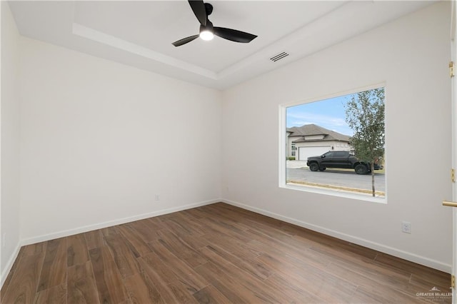 unfurnished room with wood-type flooring, a raised ceiling, and ceiling fan