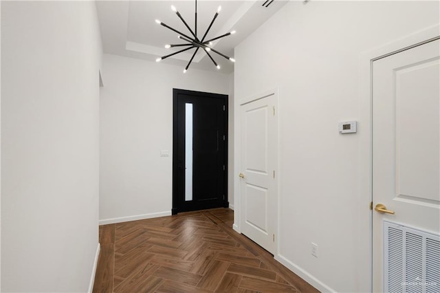 entrance foyer with dark parquet floors and a notable chandelier