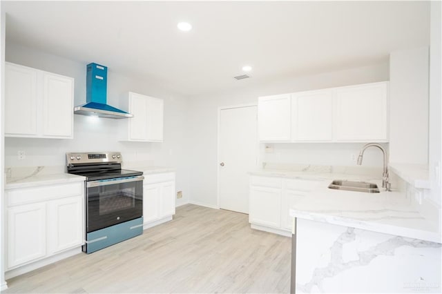 kitchen featuring wall chimney exhaust hood, sink, light hardwood / wood-style floors, white cabinetry, and stainless steel range with electric cooktop