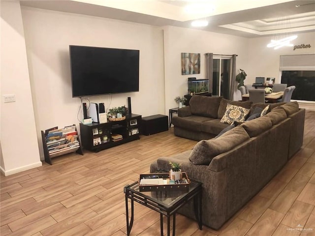 living room featuring a raised ceiling and light hardwood / wood-style floors