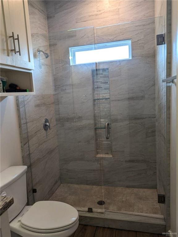 bathroom with hardwood / wood-style floors, toilet, and an enclosed shower