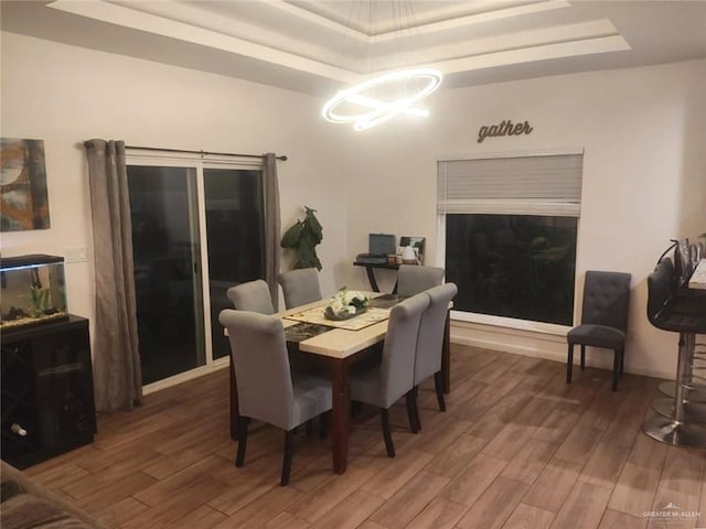 dining space with a tray ceiling and dark hardwood / wood-style flooring