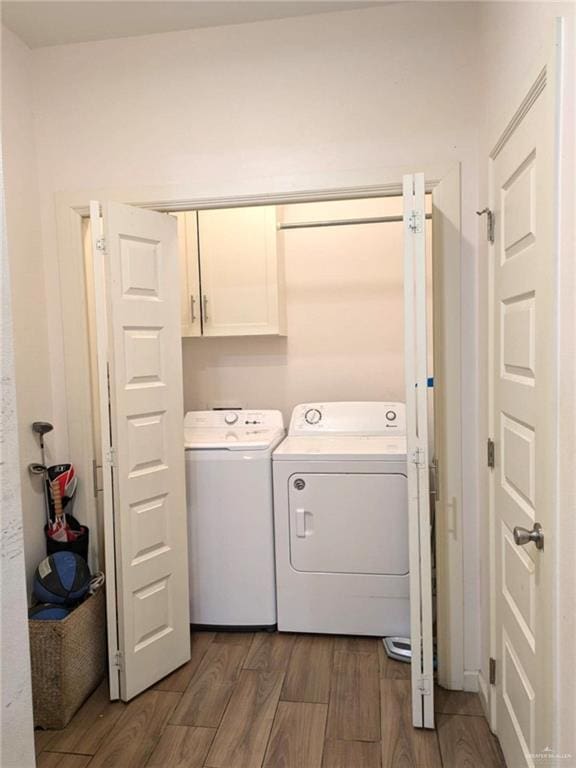 washroom with washer and dryer, dark wood-type flooring, and cabinets