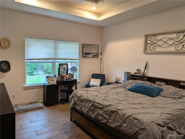 bedroom with a tray ceiling and wood-type flooring