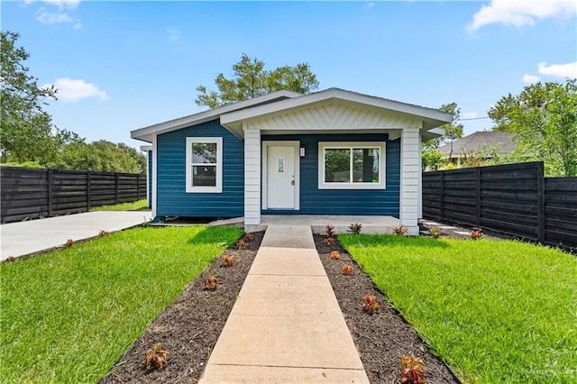 bungalow-style home featuring fence private yard, a front lawn, and covered porch
