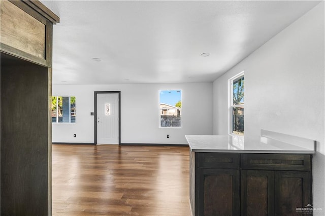 kitchen featuring baseboards, light countertops, a peninsula, and wood finished floors