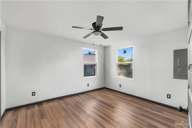 empty room featuring baseboards, electric panel, a ceiling fan, and wood finished floors