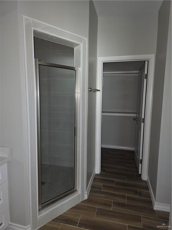 2604 Israel Ave, Alton, TX 78573 - full bathroom featuring wood finish floors, a stall shower, vanity, and baseboards