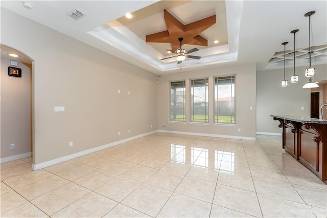 tiled spare room featuring sink, ceiling fan, and a tray ceiling