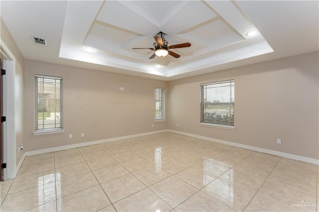 tiled spare room featuring ceiling fan, a tray ceiling, and a healthy amount of sunlight