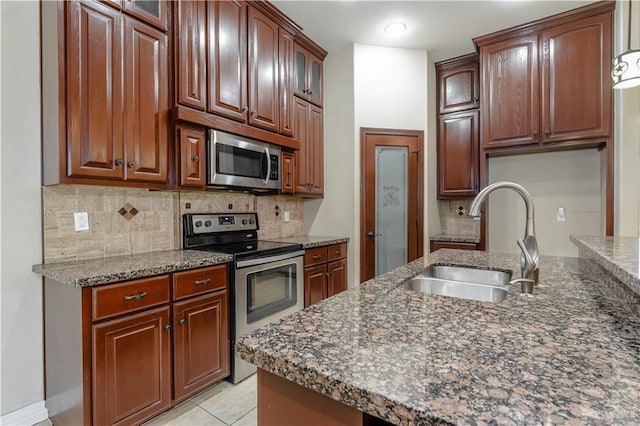 kitchen featuring light tile patterned flooring, sink, dark stone countertops, backsplash, and stainless steel appliances