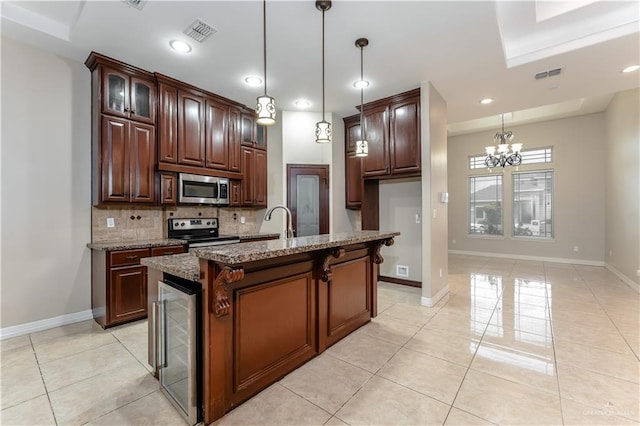 kitchen with appliances with stainless steel finishes, a kitchen island with sink, decorative light fixtures, beverage cooler, and dark stone counters