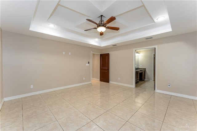 empty room featuring ceiling fan, a raised ceiling, and light tile patterned floors