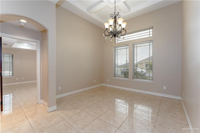 tiled empty room featuring coffered ceiling, beam ceiling, and a chandelier