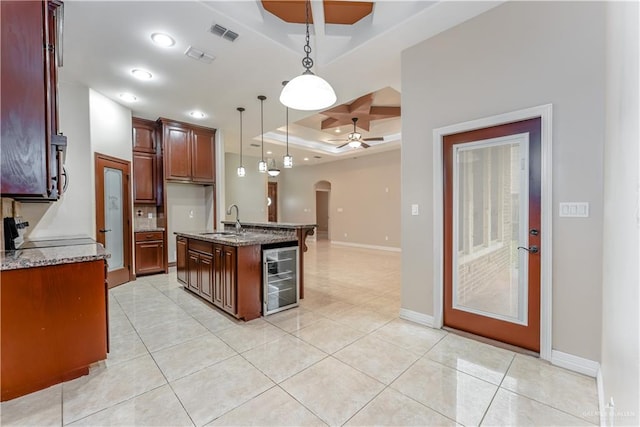 kitchen with pendant lighting, sink, stove, wine cooler, and an island with sink