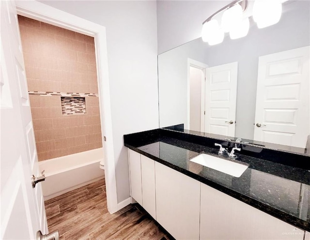 full bathroom featuring tiled shower / bath combo, toilet, vanity, and hardwood / wood-style flooring