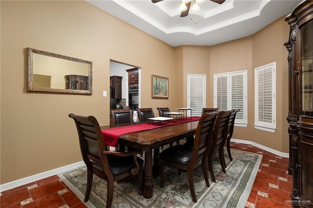 tiled dining room with a raised ceiling and ceiling fan