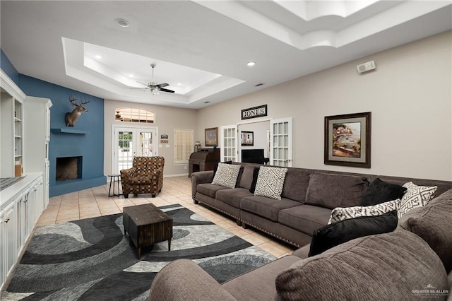 living room with french doors, a tray ceiling, light tile patterned floors, and ceiling fan