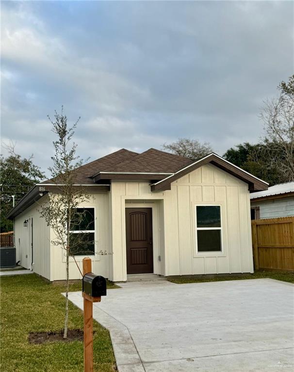 view of front of property with central air condition unit and a front yard