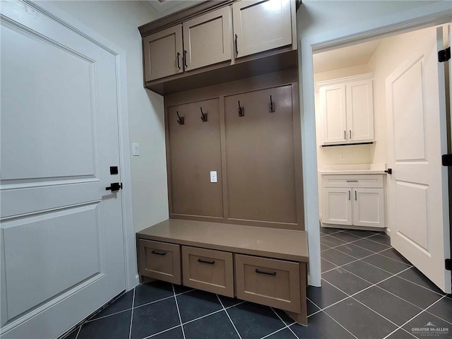 mudroom with dark tile patterned floors