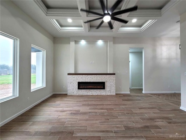 unfurnished living room featuring beamed ceiling, ceiling fan, a stone fireplace, and coffered ceiling