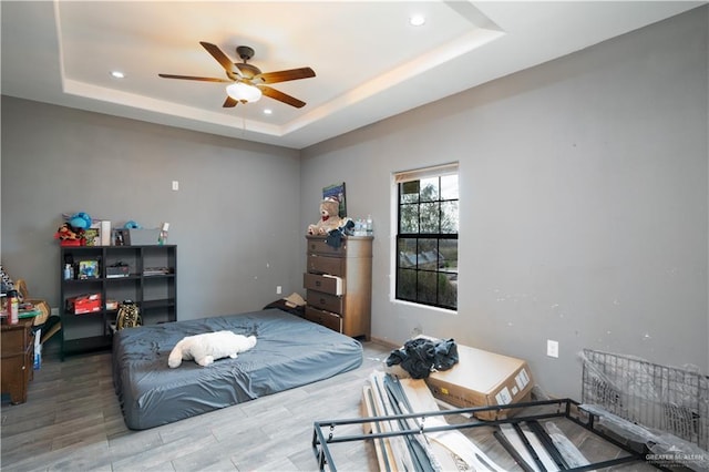 bedroom featuring ceiling fan, a raised ceiling, wood finished floors, and recessed lighting