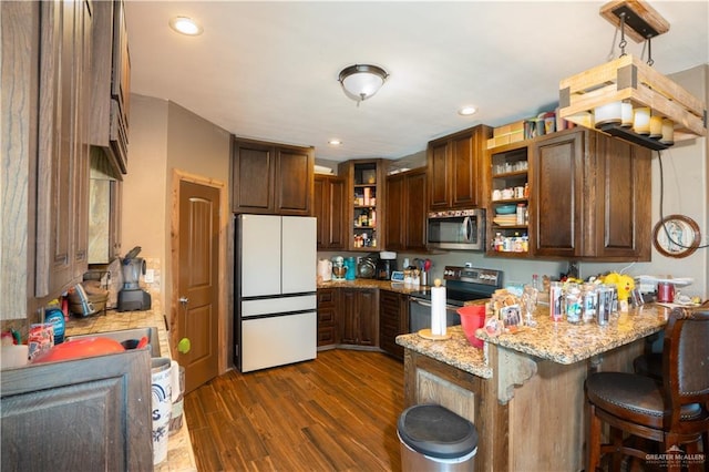 kitchen with dark wood-style floors, appliances with stainless steel finishes, light stone counters, a peninsula, and open shelves