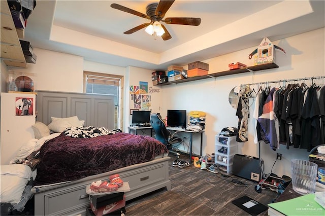 bedroom featuring a tray ceiling, wood finish floors, and a ceiling fan