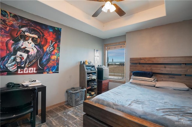 bedroom featuring a ceiling fan, wood tiled floor, a raised ceiling, and baseboards