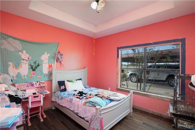 bedroom with a tray ceiling and wood finish floors