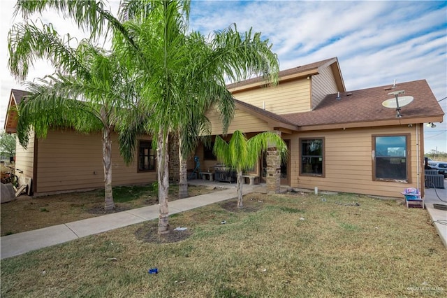 rear view of property with a patio area, a shingled roof, and a lawn