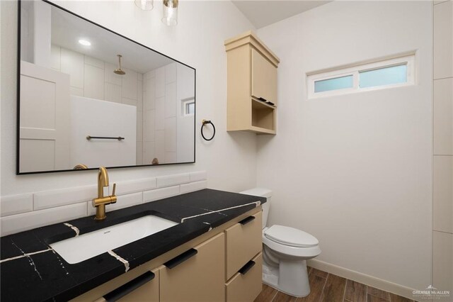 9218 N 25th Ln, Mcallen, TX 78504 - bathroom featuring wood finished floors, toilet, vanity, decorative backsplash, and baseboards