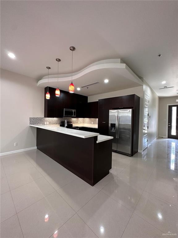 kitchen featuring kitchen peninsula, pendant lighting, stainless steel appliances, and light tile patterned flooring