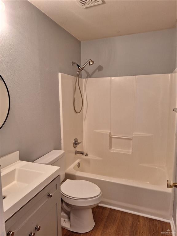 full bathroom featuring hardwood / wood-style flooring, vanity, toilet, and washtub / shower combination