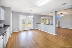 kitchen featuring white cabinetry, dark wood-type flooring, stainless steel dishwasher, and decorative light fixtures