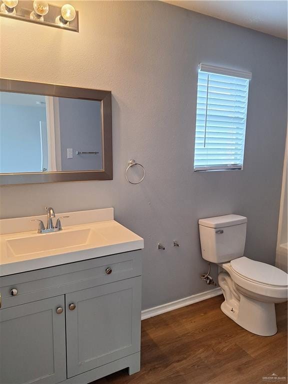 bathroom with hardwood / wood-style floors, vanity, and toilet