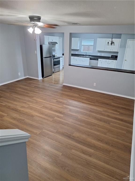 unfurnished living room featuring ceiling fan, sink, and light wood-type flooring