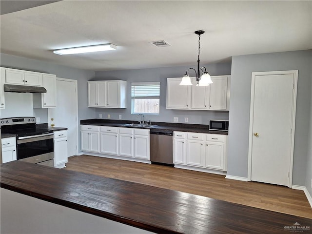 kitchen with an inviting chandelier, sink, appliances with stainless steel finishes, decorative light fixtures, and white cabinetry