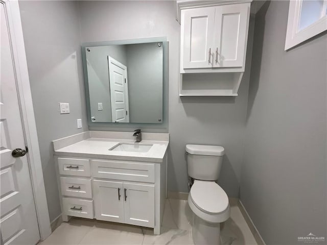 bathroom with toilet, vanity, and baseboards