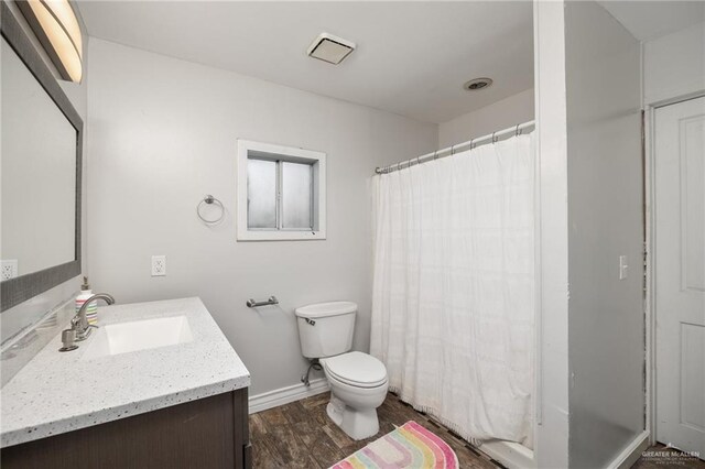 bathroom featuring vanity, hardwood / wood-style flooring, toilet, and curtained shower