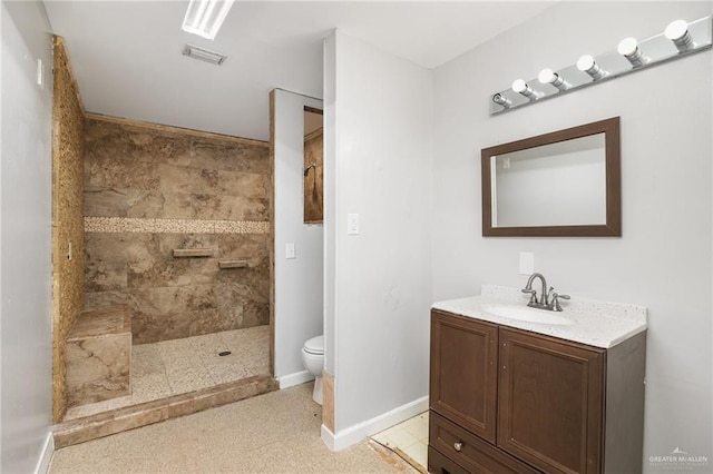 bathroom featuring a tile shower, vanity, toilet, and tile patterned floors