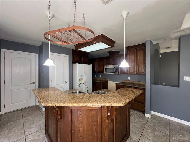 2700 Duke Ave, Mcallen, TX 78504 - kitchen with stainless steel microwave, white refrigerator with ice dispenser, a center island with sink, light tile patterned floors, and a sink