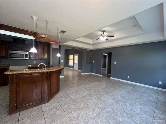 2700 Duke Ave, Mcallen, TX 78504 - kitchen featuring stainless steel microwave, a raised ceiling, arched walkways, a ceiling fan, and open floor plan